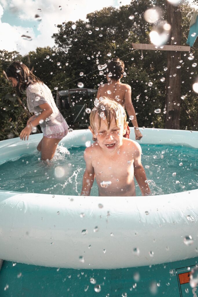 Happy children enjoying a fun time in an outdoor inflatable pool on a sunny day, creating joyful splashes of water.