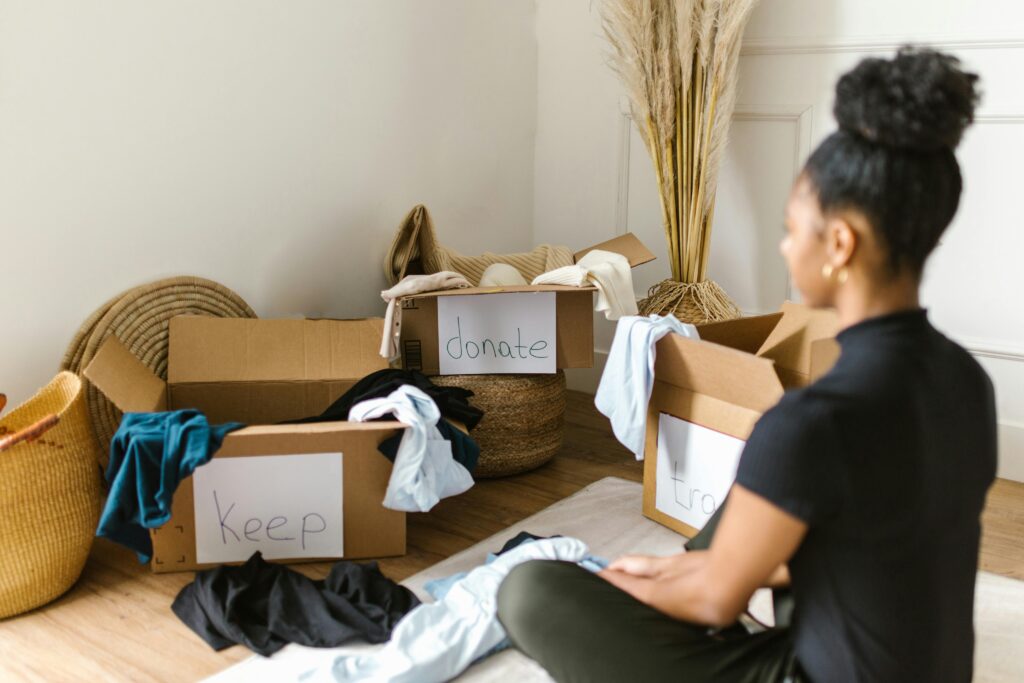 A woman organizing clothes into labeled boxes for donation and keeping.