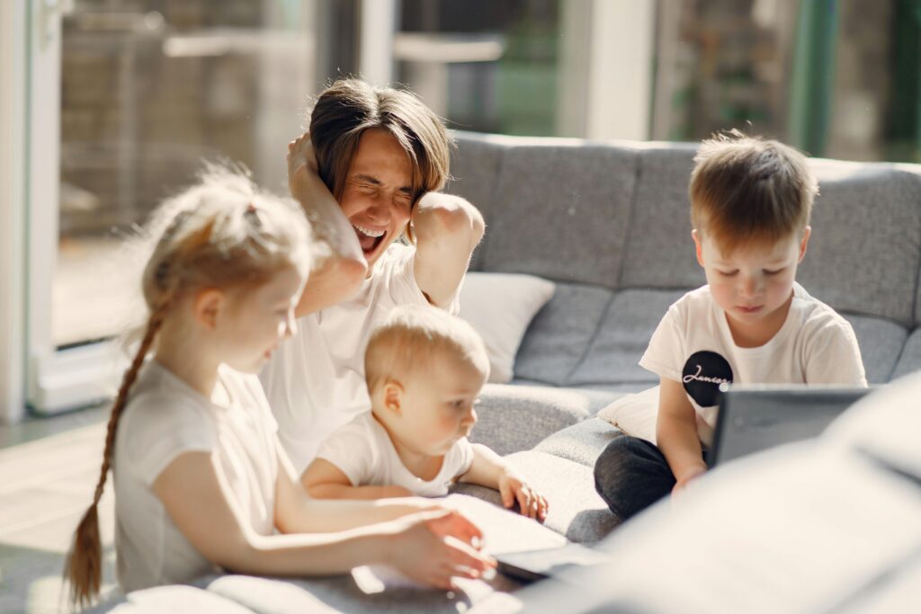 Woman going mad while sitting with little kids playing together on sofa in well lit room