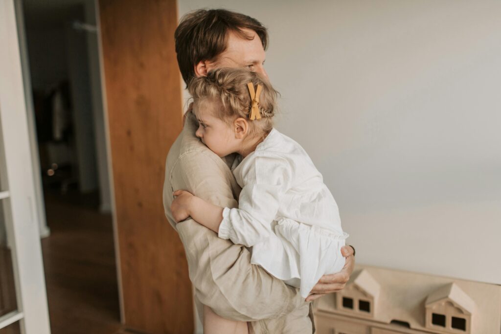 A father lovingly embraces his young daughter, showcasing tender family affection.