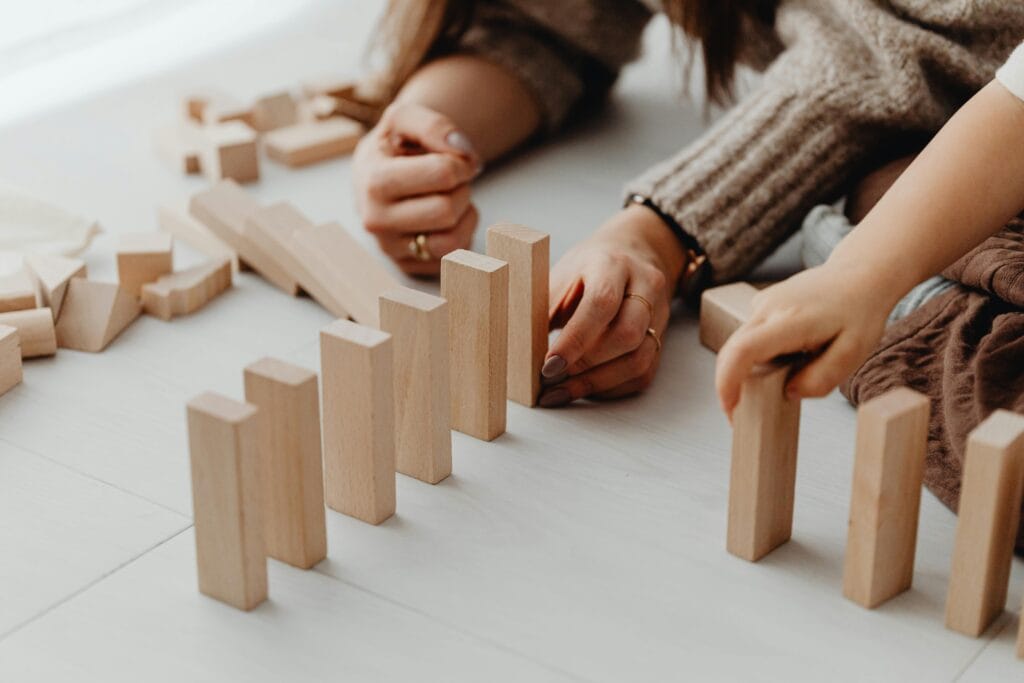 A child and parent engaging in creative play with wooden blocks indoors.